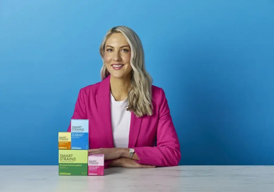 Dr. Megan Rossi holding a box of SMART STRAINS live bacteria supplements in a retail store aisle.