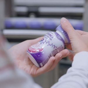 Worker inspecting a Fortimel medical nutrition bottle on Danone's Steenvoorde production line