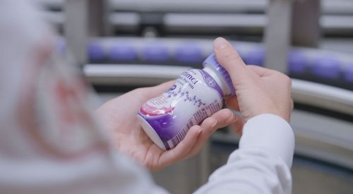 Worker inspecting a Fortimel medical nutrition bottle on Danone's Steenvoorde production line