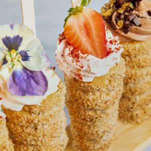 A wooden stick holding various desserts, showcasing the Trend Report on Twist it Up donut cones.