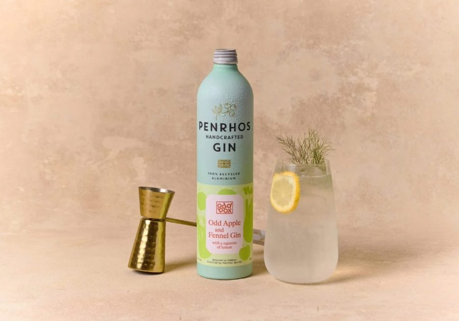 A bottle of Penrhos handcrafted gin beside a jigger and a glass of gin with a lemon slice and a sprig of herb