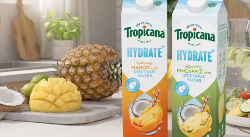 Two cartons of Tropicana Hydrate plus coconut water drink in Mango and Pineapple flavors on a bright kitchen counter next to a fresh whole pineapple, sliced mango, and coconut